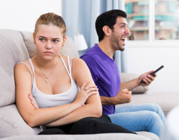 garota desapontada no sofá enquanto o homem assiste tv - umbrage - fotografias e filmes do acervo
