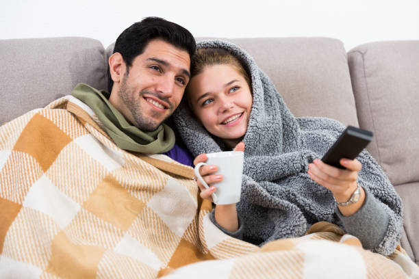 istock Loving couple snuggling on sofa watching TV 1266181831