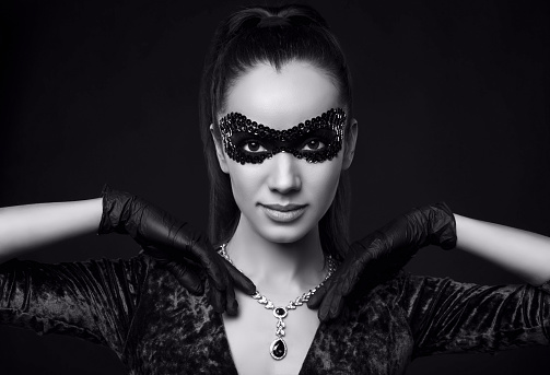 Portrait of charming elegant brunette woman in beautiful purple dress, sequins mask and black gloves posing with a stolen diamond necklace