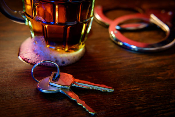 Alcohol Keys Handcuffs Mug of frothy beer with handcuffs and keys symbolizing drunk driving arrest driving under the influence stock pictures, royalty-free photos & images