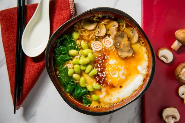 Spicy edamame and narutomaki spiral ramen noodle soup with runny fried egg