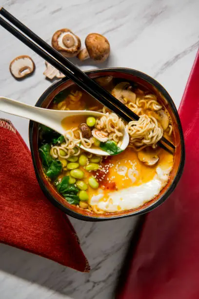 Spicy edamame and narutomaki spiral ramen noodle soup with runny fried egg