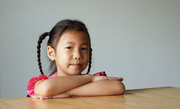 istock Asian little girl cross her arm sit on table 1266201627