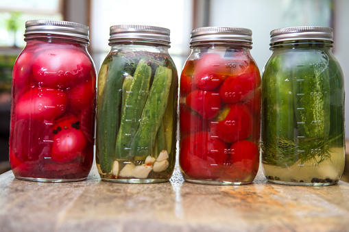 Row of homemade rustic organic pickled beet eggs cucumbers and cherry peppers
