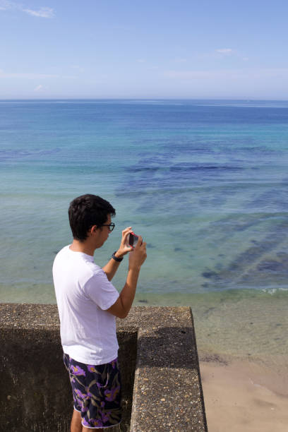 istock Boy taking picture of the ocean with a mobile device. 1266205600