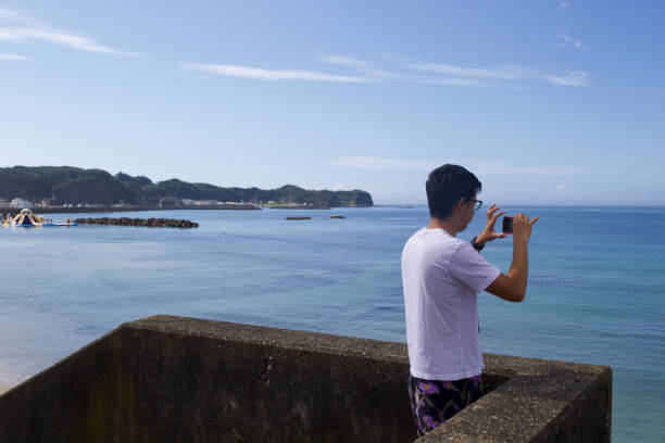 istock Boy taking picture of the ocean with a mobile device. 1266205604
