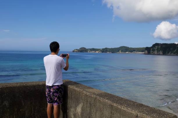 istock Boy taking picture of the ocean with a mobile device. 1266205606
