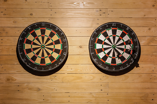 Front view shot of two empty dartboards hanging on the wooden wall