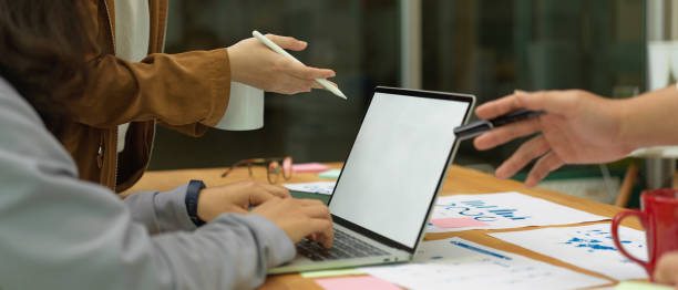 istock Office workers consulting on their project with mock up laptop and paperwork on meeting table 1266206933