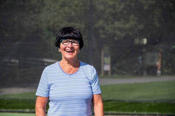 Portrait of an active senior woman An active senior woman enjoys playing pickleball at a public court. She is enjoying her retirement years. Active senior woman outdoors tennis senior adult adult mature adult stock pictures, royalty-free photos & images