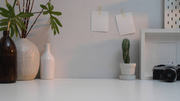 istock Workplace with copy space, camera, frame, vases, plant house and notepad in home office 1266208469