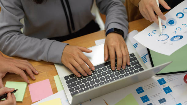 istock Office workers briefing on their project with paperwork and laptop on meeting table 1266209386