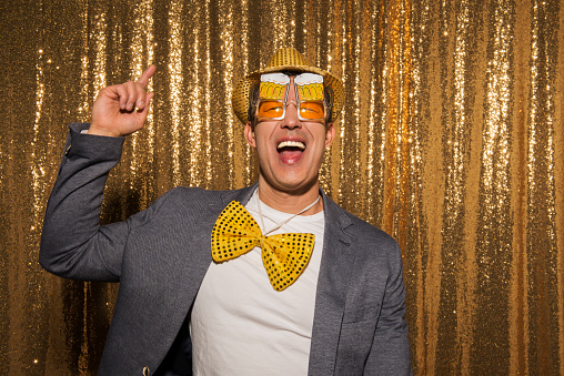 Portrait of smiling mature man wearing hat and glasses gesturing during the party.