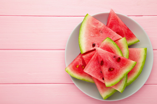 Fresh ripe striped sliced watermelon on white wooden background.