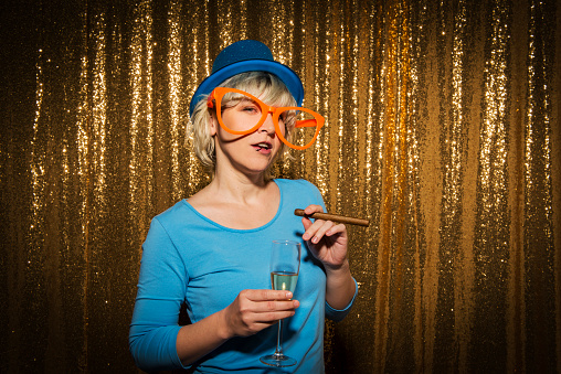 Portrait of woman with fake cigar and champagne flute during the party.