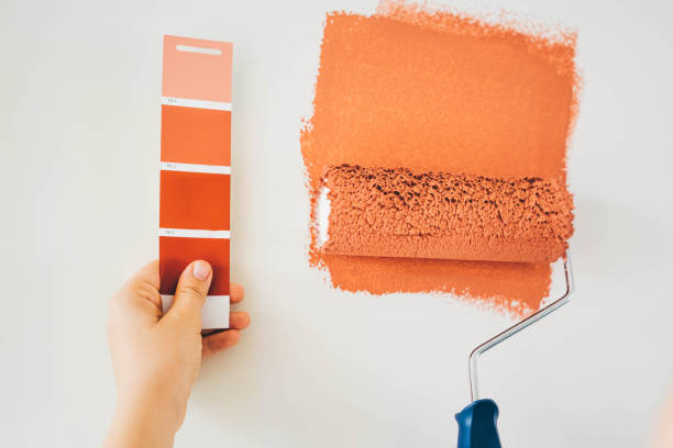 woman painting wall. woman painting wall. close up hand with paint roller and color swatch. Repair and house renovation concept. terracotta color stock pictures, royalty-free photos & images