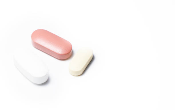 istock One Brown and two white pills on white background. 1266229252