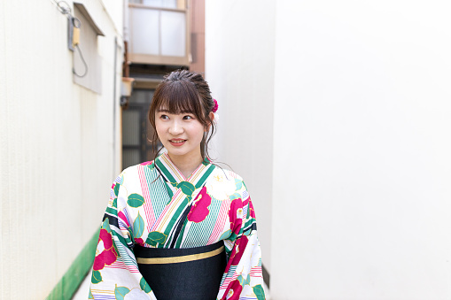 Young woman in yukata walking between white wall