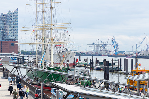 Hamburg, Germany - June 8, 2020: The Pier of the Landungsbruecken und Ueberseebruecke with the entertainment-ships Cap San Diego und Rickmer Rickmers. In the background is the elbe philharmonic hall. People are going by.