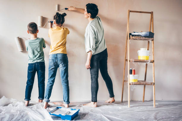 madre feliz, 
hija e hijo pintura pared con rodillo. - repairing apartment home improvement painting fotografías e imágenes de stock