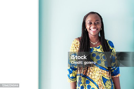 istock portrait of smiling african woman in front of blue wall 1266234544