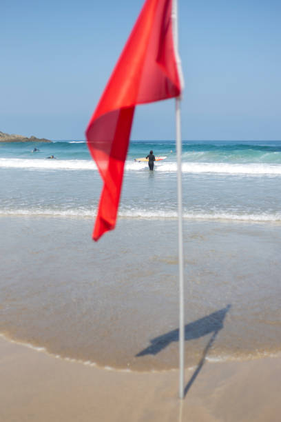 istock Beach and Red Flag. Surfers surfing in the background 1266242275