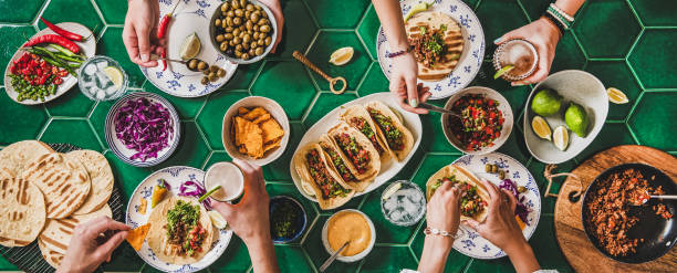 fiesta de tacos en casa con tortillas, salsa de tomate y manos de la gente - taco alimento fotos fotografías e imágenes de stock