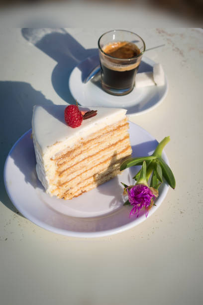 honey birthday cake with buttercream, decorated with raspberries, next to an espresso Cup. The photo was taken outside in the sunlight