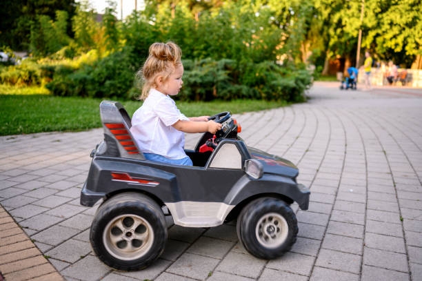 leuk babymeisje in elektrische speelgoedauto - speelgoedauto stockfoto's en -beelden