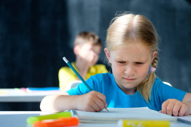 Schoolgirl does homework at school desk