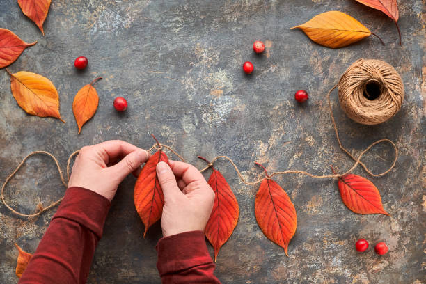 istock Fall DIY decorations from natural materials. Making garland with cord and Autumn leaves. 1266254409