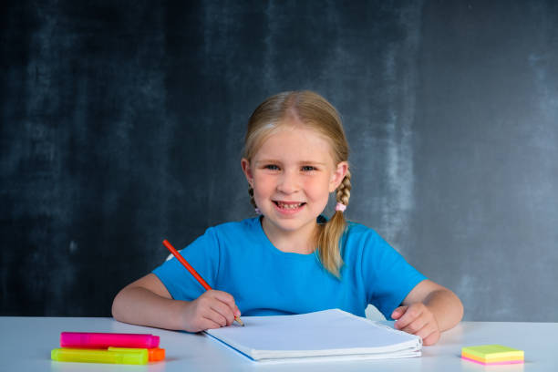 Schoolgirl does homework at school desk Schoolgirl does homework at school desk first grade classroom stock pictures, royalty-free photos & images