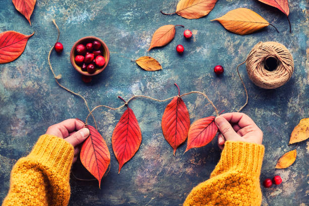 istock Fall DIY decorations from natural materials. Making garland with hemp cord and vibrant red Autumn leaves. 1266254553
