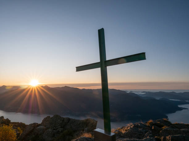 istock View from mountain top at sunrise and religious catholic cross on peak 1266257535