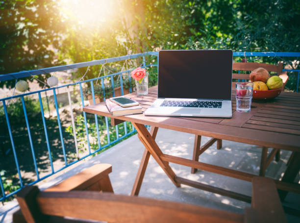 laptop auf holztischem tisch auf einer sonnigen sommerterrasse, sommerstimmung und urlaub in einem landhaus - campingplatz stock-fotos und bilder