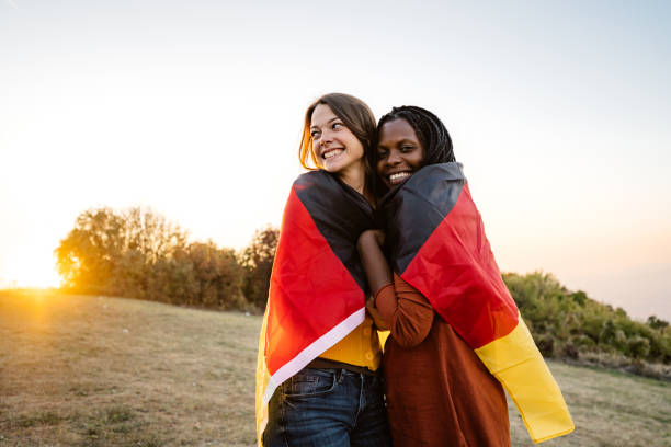 две многоэтнические женщины с немецким флагом - german culture people women germany стоковые фото и изображения