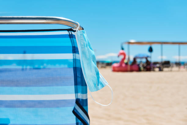 istock face mask hanging from a deck chair on the beach 1266265537