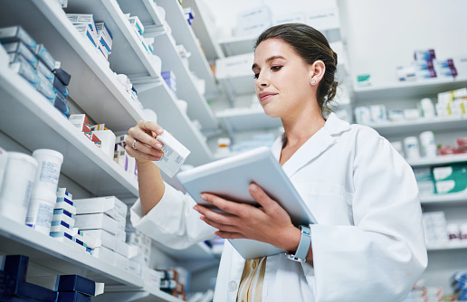 Shot of a young woman using a digital tablet while working in a pharmacy