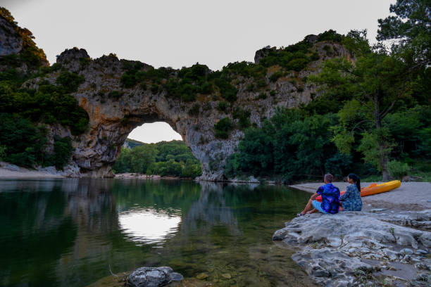 coppia sulla spiaggia sul fiume nell'ardeche france pont d arc, ardeche francia, vista dell'arco narurale a vallon pont d'arc nel canyon di ardeche in francia - canoeing people traveling camping couple foto e immagini stock