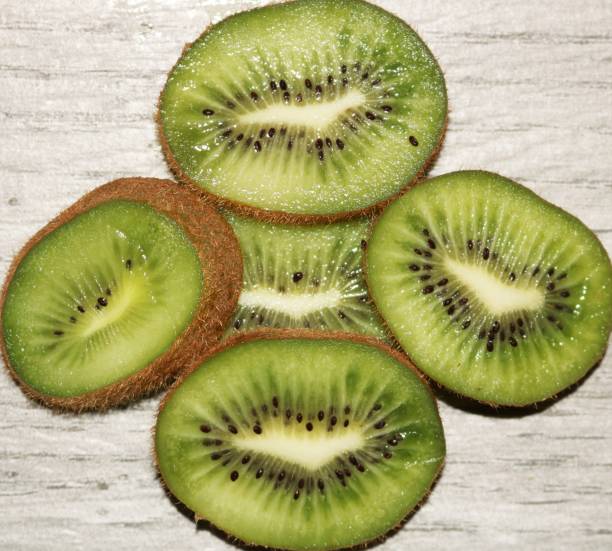 istock Five Slices of Kiwi Fruit, in a Circle, on Gray Table 1266268050