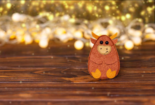 Xmas chinese bull decorated with garland lights. Defocused image of illuminated lights at night. Empty rustic wooden table with blurred lights. New year, winter, Christmas holiday, festive background