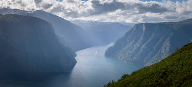 cruise ship inbetween mountain cliff in fjord sunlight haze norway - aurlandfjord imagens e fotografias de stock