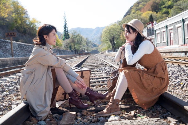 istock Young girlfriends sitting on the tracks 1266271118