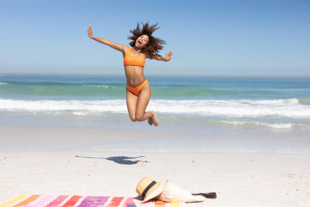 Mixed race woman jumping on the beach