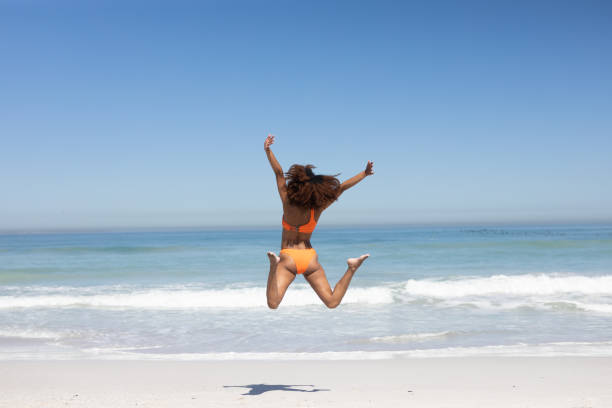 istock Mixed race woman jumping on the beach 1266275409