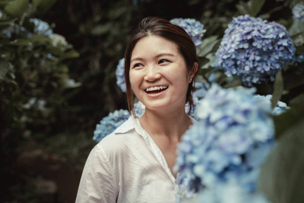 青いアジサイに囲まれた庭の若いアジア人女性の肖像画。