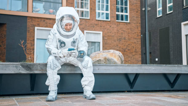 istock Handsome Man in Spacesuit is Using a Smartphone Mobile Phone. Happy Astronaut is Texting a Message and Browsing Social Media. Spaceman in White Futuristic Suit with Technological Panel on His Hand. 1266285700
