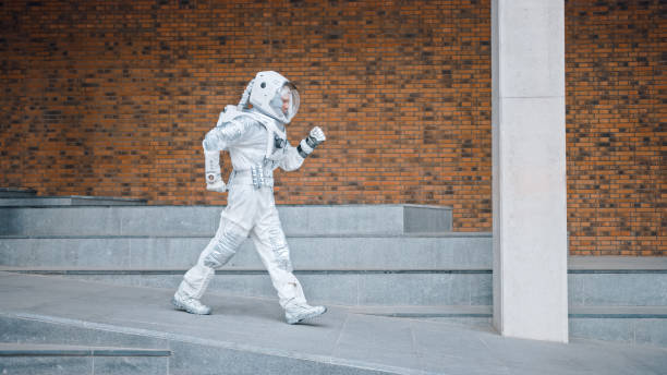 istock Handsome Man in Spacesuit is Dancing on Concrete Stairs. Astronaut is Happy and Makes Creative Dance Moves. Successful Spaceman in White Futuristic Suit with Technological Panel on His Hand. 1266285709