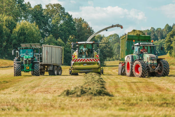 la mietitrebbia claas jaguar 930, un trattore john deere 6175r e un fendt 926 con rimorchio krone zx400gl funzionano su un campo. - editorial horizontal farmer occupation foto e immagini stock