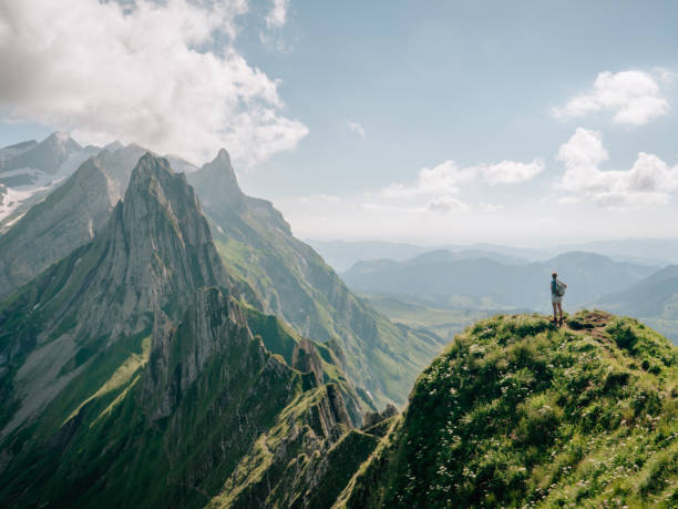 istock Distant woman standing on top of mountain peak 1266292747
